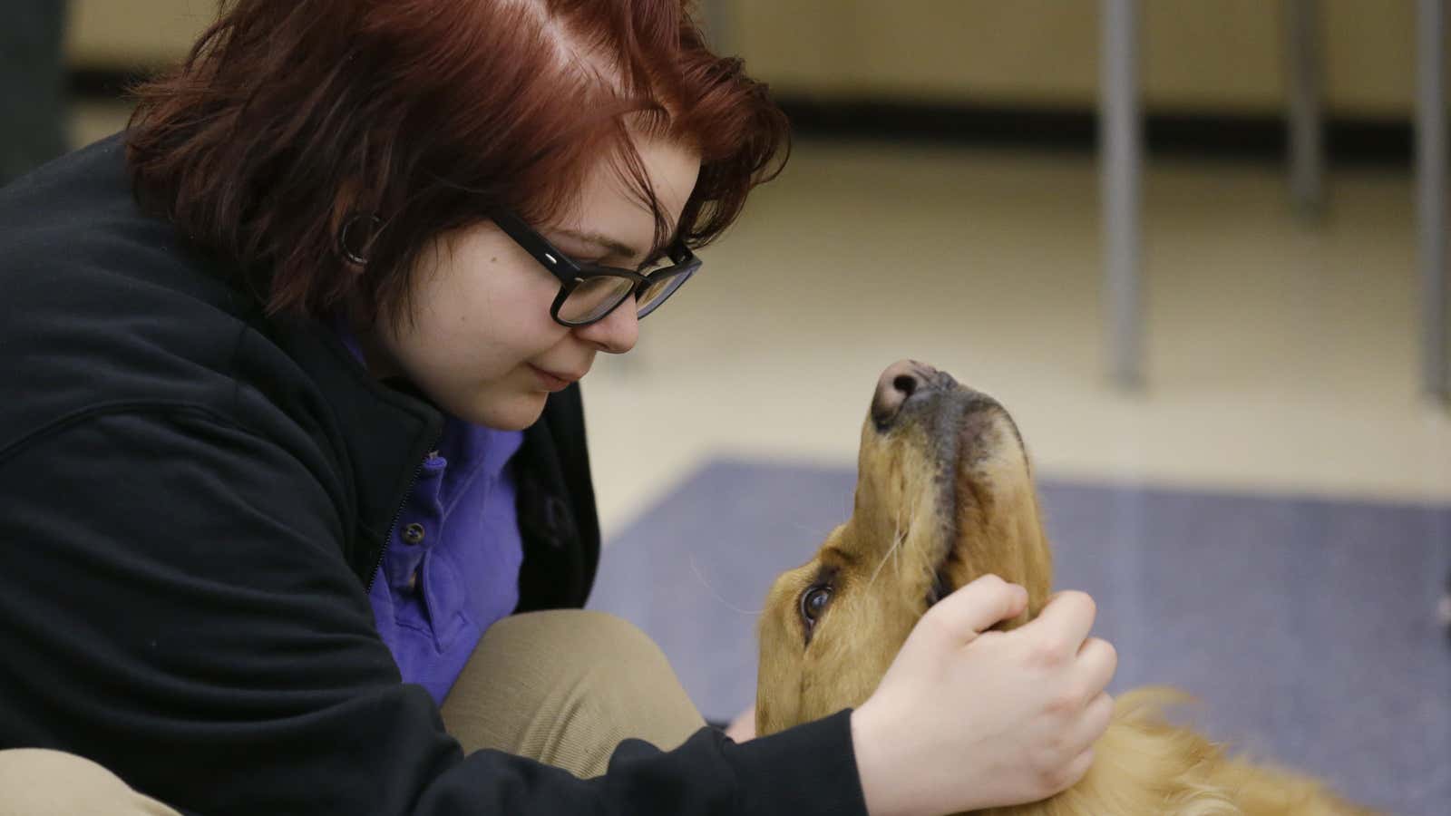 In this Monday, March 13, 2017 photo, Sophie Herrick pets Banks as students and teachers gather for an all-school meeting called “circle” at Hope Academy…