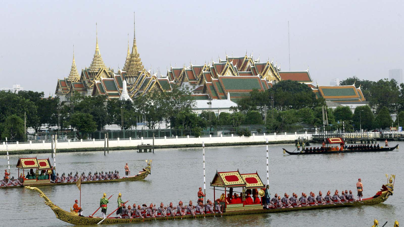 Ornate barges pass Bangkok’s Grand Palace.