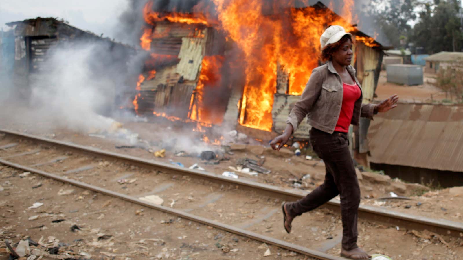 A woman walks past a burned shack, in Kibera slum, in Nairobi, Kenya.