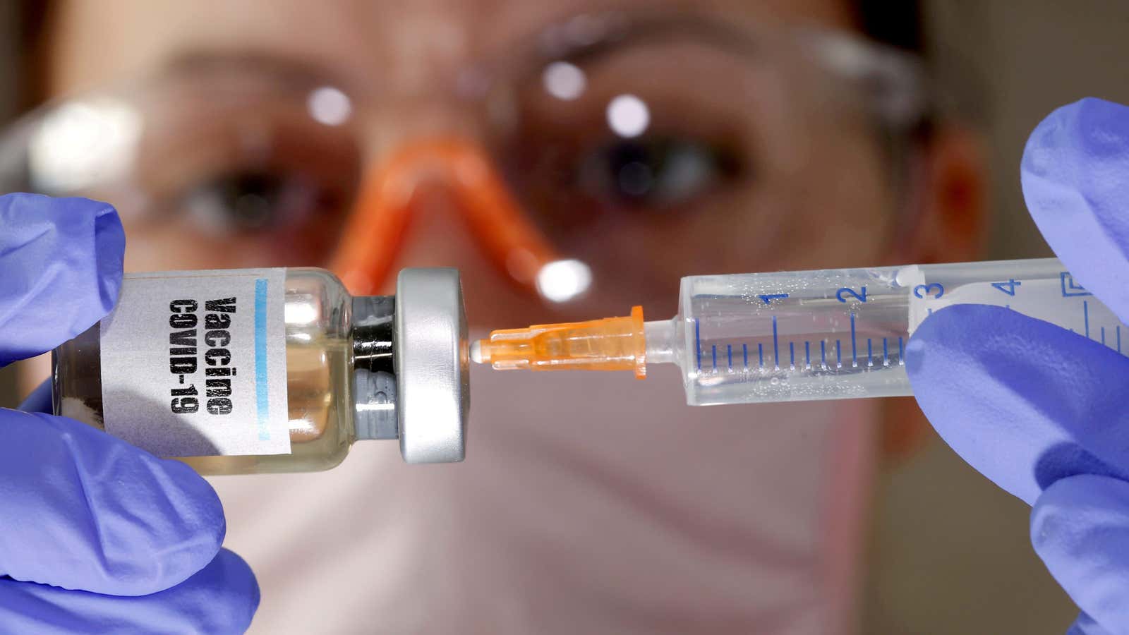 A woman holds a small bottle labeled with a “Vaccine COVID-19” sticker and a medical syringe in this illustration taken April 10, 2020.