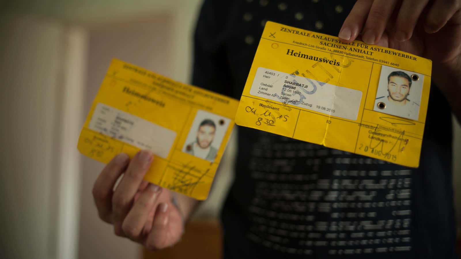 Identification please. A migrant holds documents he was issued when he first arrived in Germany.