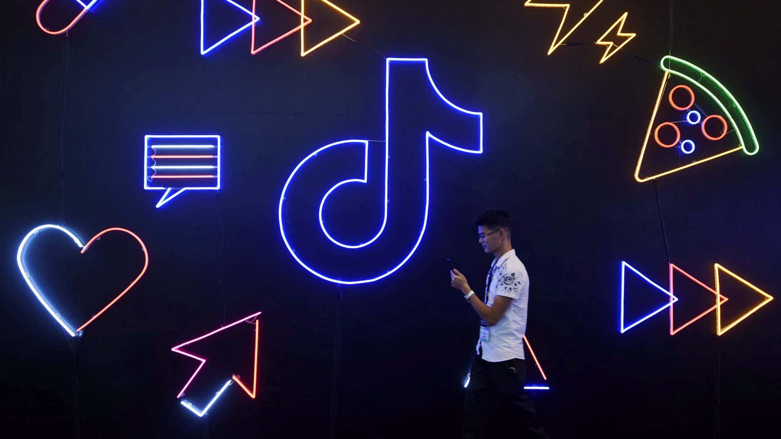 A man holding a phone walks past a sign of Chinese company ByteDance’s app TikTok, known locally as Douyin, at the International Artificial Products Expo…