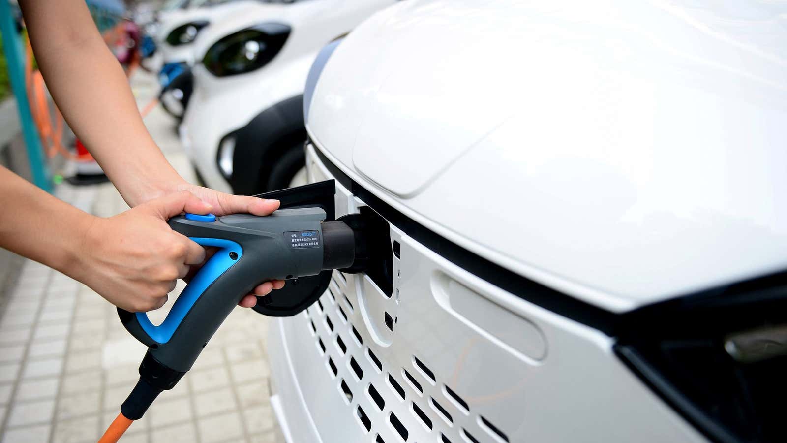 A staff member hooks up a charging cable to an electric vehicle (EV) at a charging station in Liuzhou, Guangxi Zhuang Autonomous Region, China July…