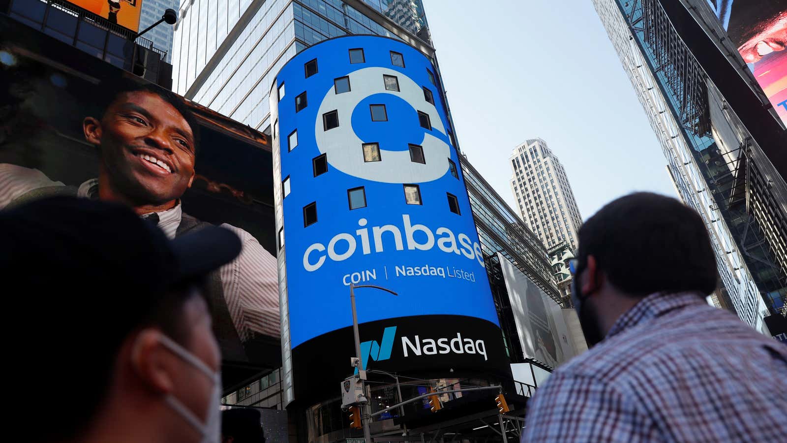 People watch as the logo for Coinbase Global Inc, the biggest U.S. cryptocurrency exchange, is displayed on the Nasdaq MarketSite jumbotron at Times Square in…