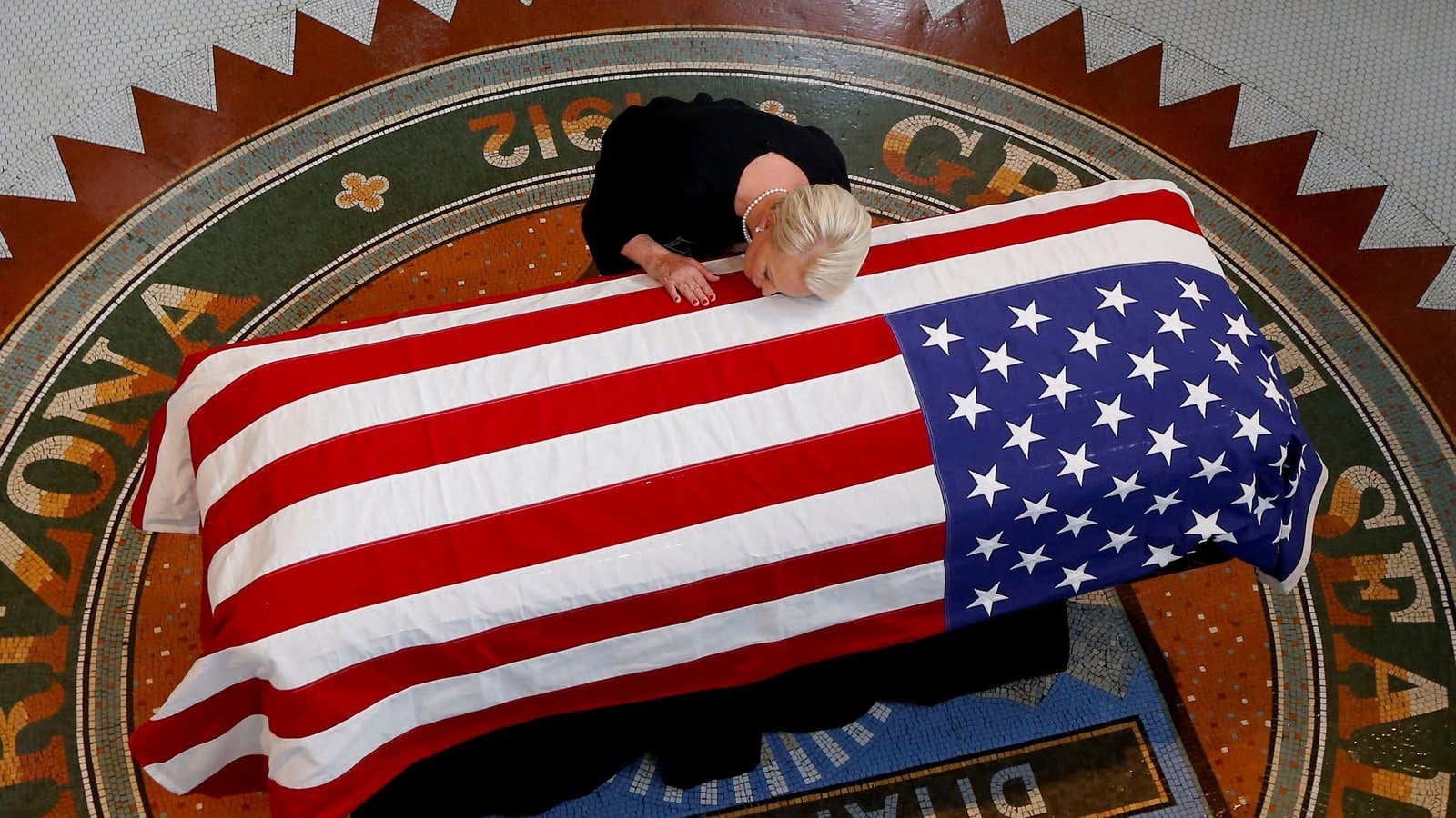 Cindy McCain rests her head on her husband’s casket at the Arizona state house.