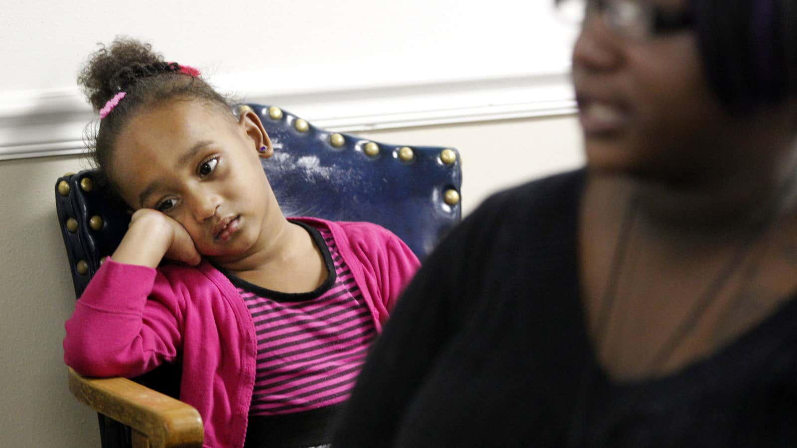 A child waits with her mother at a homeless shelter.