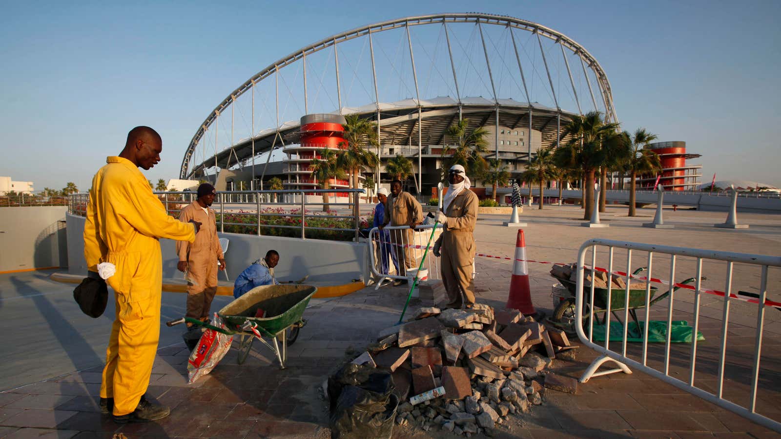 Workers clean up the road outside the Khalifa stadium where the first match of the AFC Asian Cup will take place, in Doha, Qatar, Monday,…