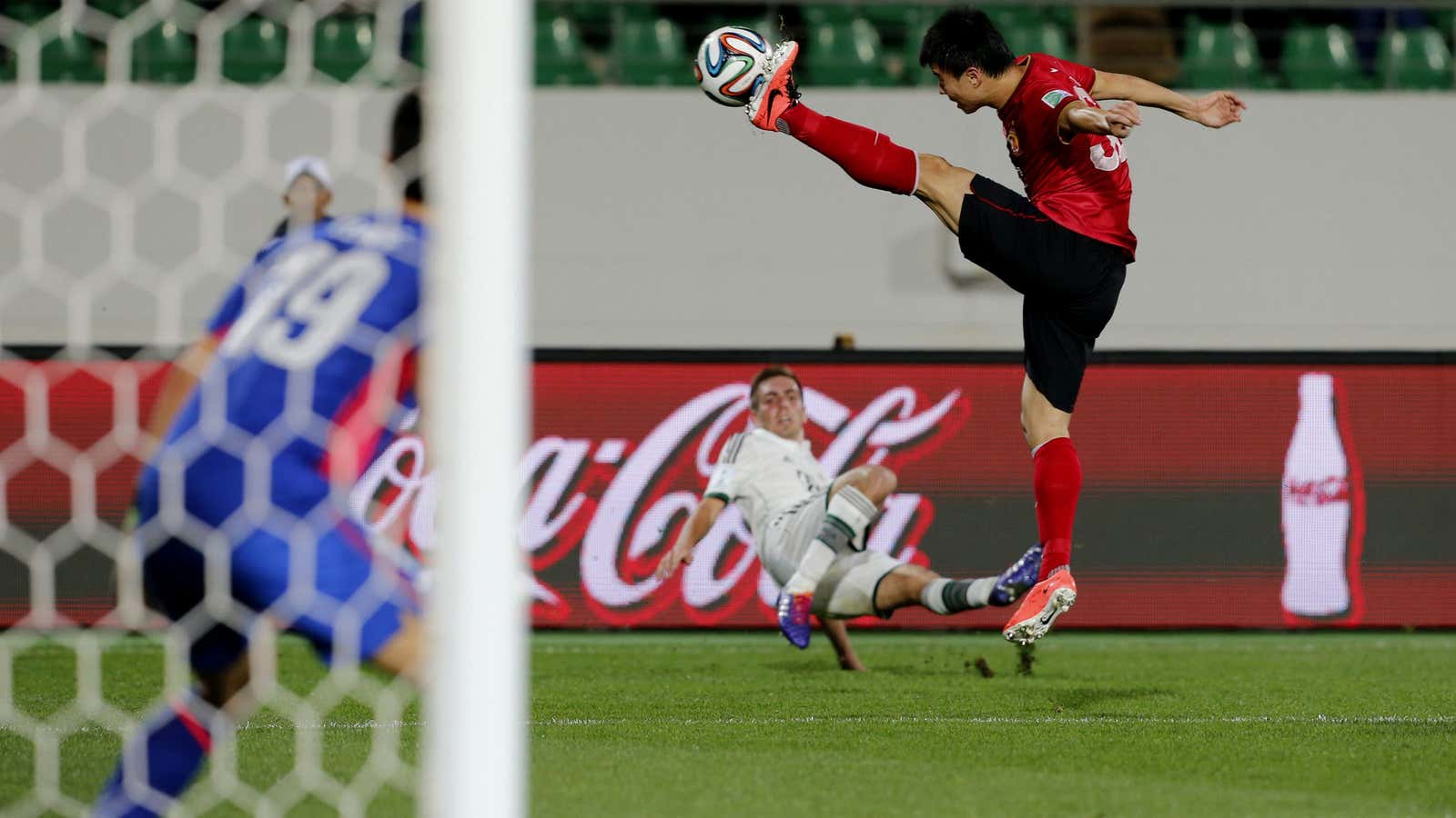 Guangzhou Evergrande’s Yi Teng tries to stop a shot by Bayern Munich’s Philipp Lahm during their teams’ FIFA Club World Cup soccer match.