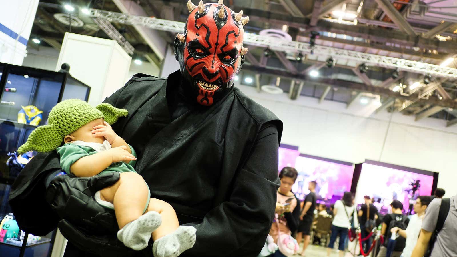 A cosplayer dressed as Darth Maul from Star Wars, carrying a child dressed in a Yoda hat, poses during the Singapore Comic Con, in Singapore…