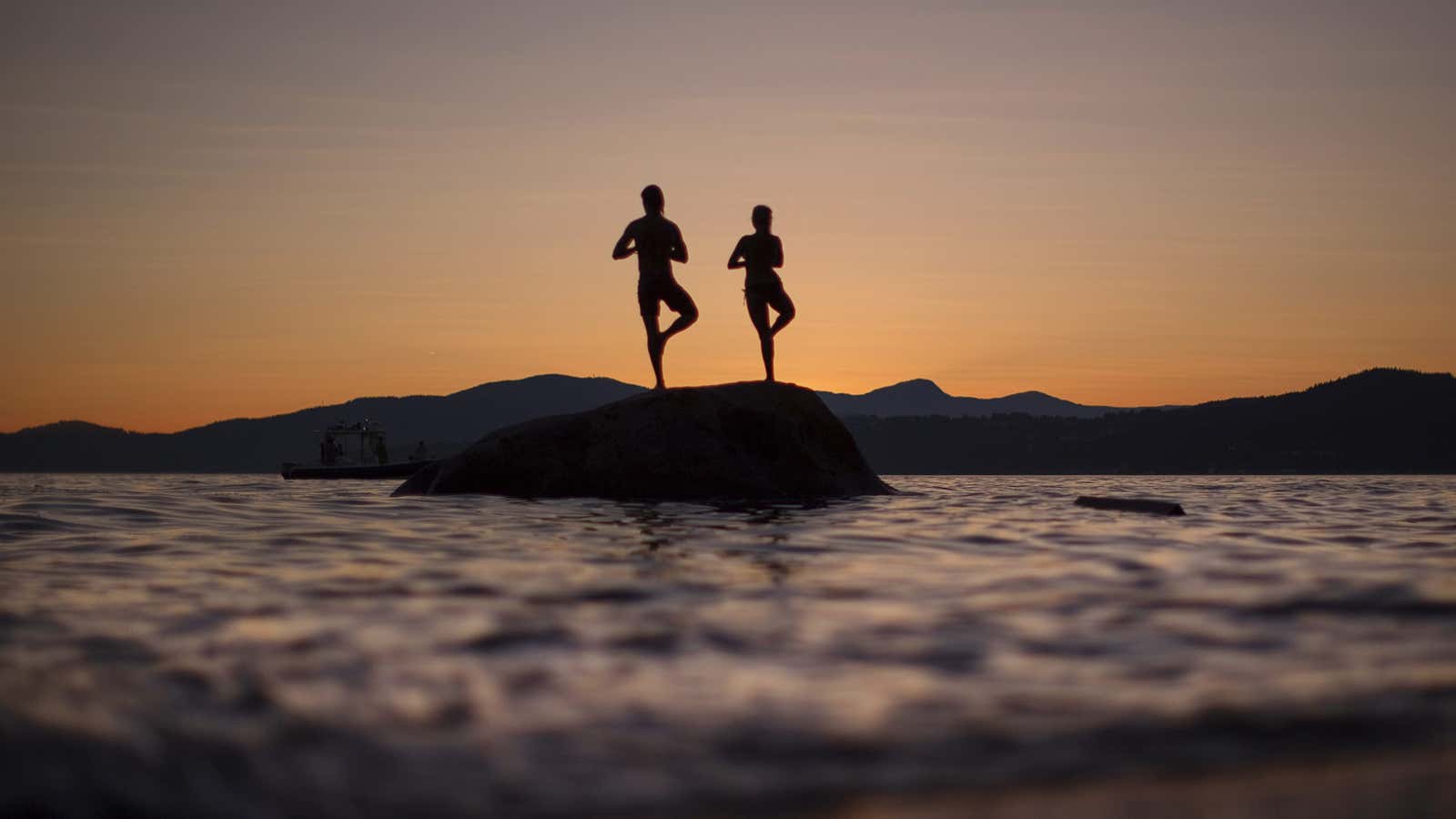 A couple stand on a rock facing the sunset along the shores of English Bay in Vancouver, British Columbia July 23, 2013. REUTERS/Andy Clark (CANADA – Tags: SOCIETY) – GM1E97O114A01