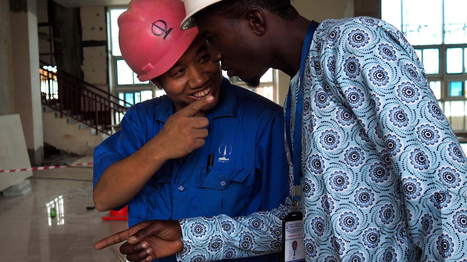 A Chinese worker jokes with his Nigerian counterpart during  construction of Lagos at light rail system.