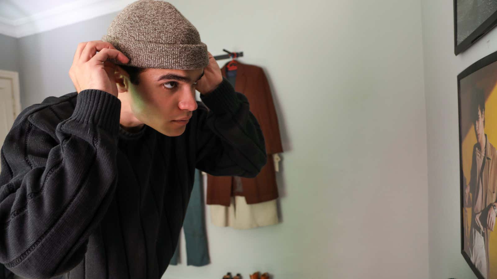 Jordanian fashion blogger Ahmad Aburub adjusts his hat while looking in the mirror in his room,