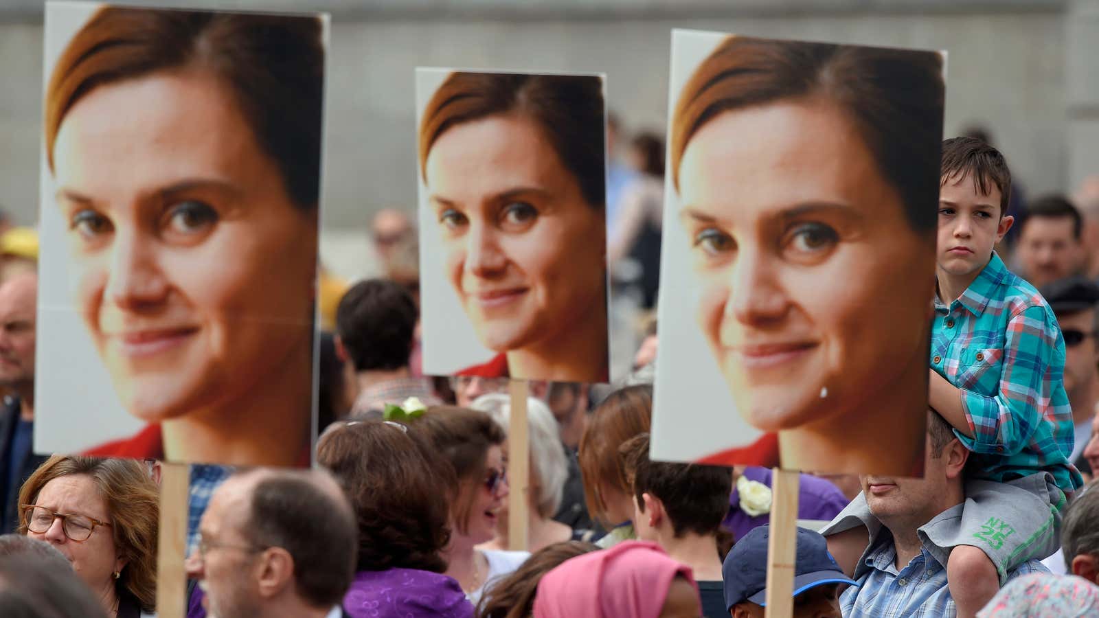 People hold banners of Jo Cox during a special service .