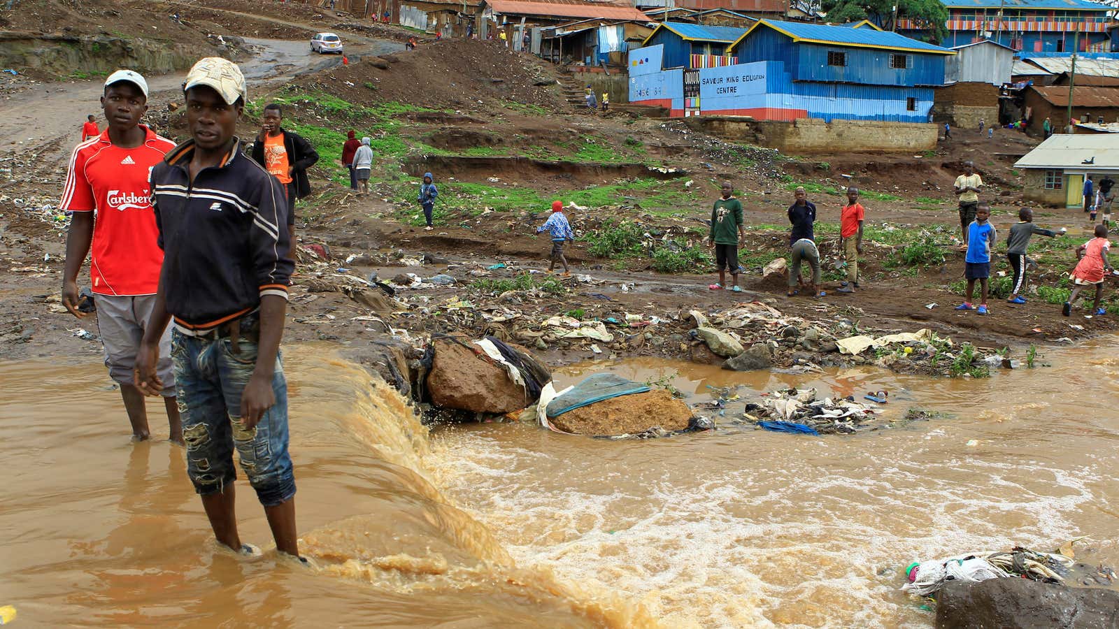 People stand in flood water near the Nairobi river in the Kibera slum in Nairobi, Kenya. Dec. 3, 2019.