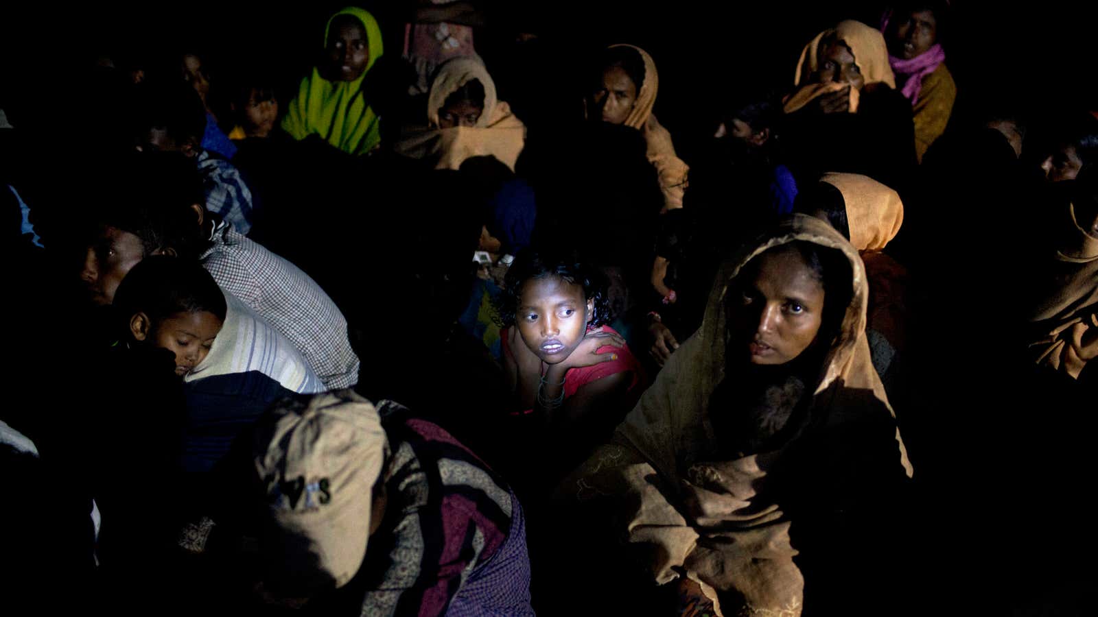 Light from a torch falls on the face of a Rohingya Muslim girl sitting with a group on a raft made with plastic containers on which they crossed over from Myanmar into Bangladesh.