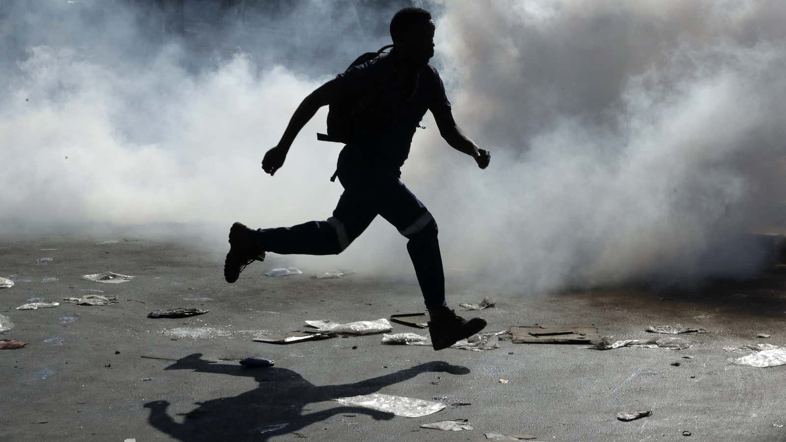 A man runs away from teargas after making off with goods from a store in Germiston, east of Johannesburg, South Africa, Sep. 3, 2019.