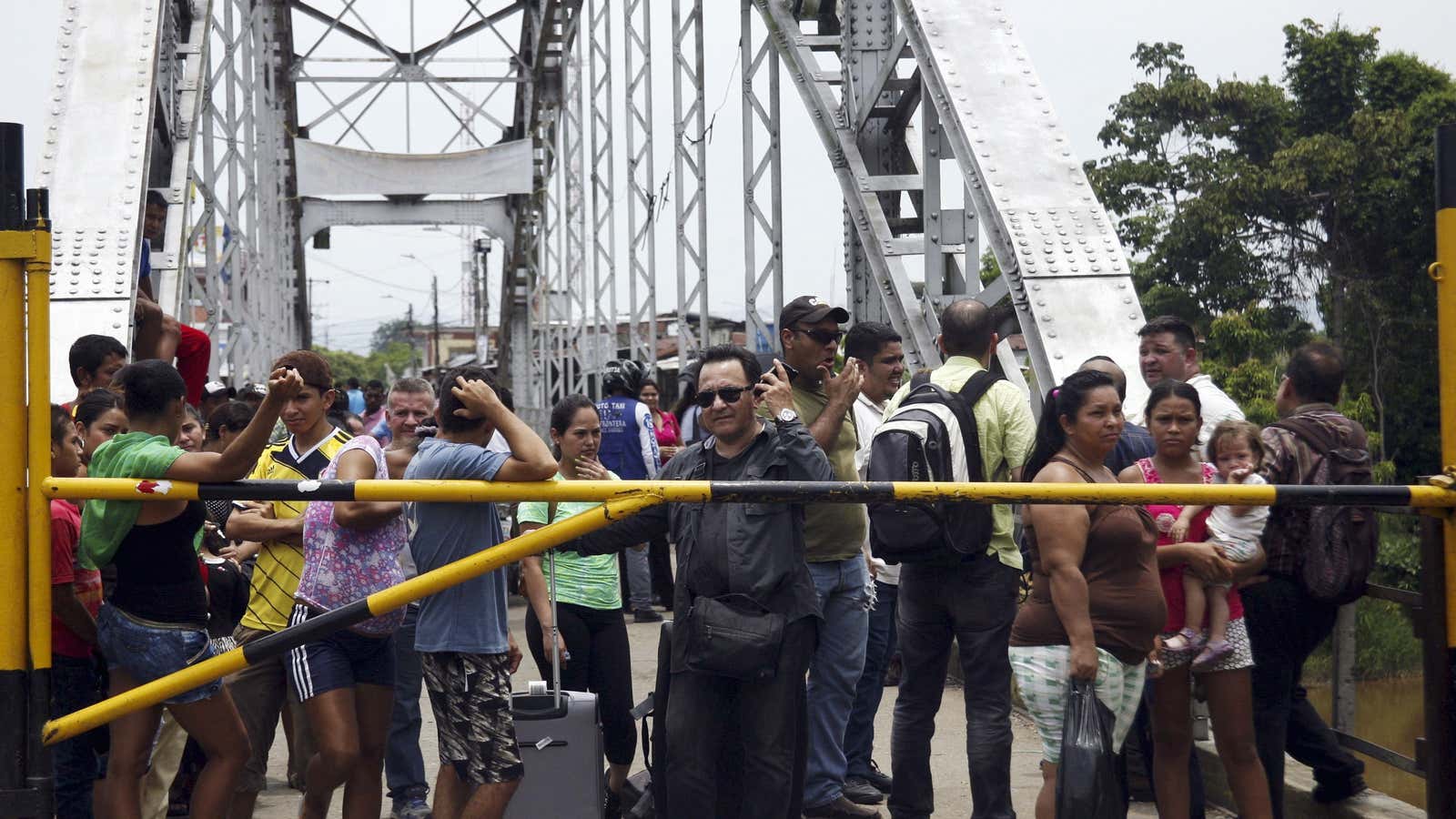 People stand next to a closed gate as they wait to try to cross La Union international bridge, on the border with Colombia at Boca de Grita in Tachira state, Venezuela.