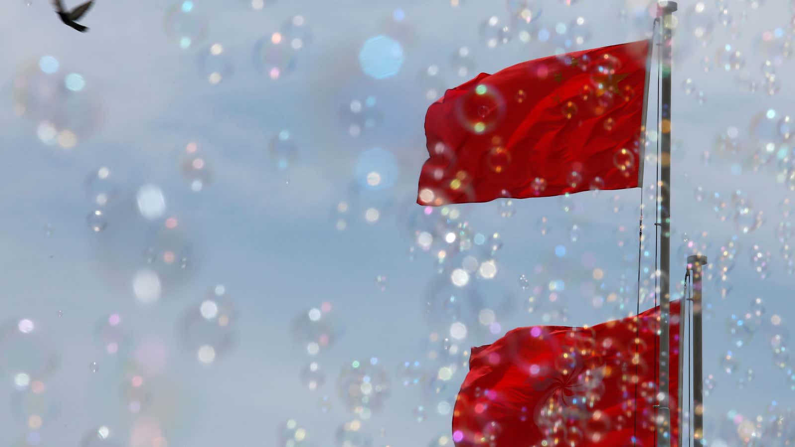 Bubbles are seen in front of a Chinese national flag (top) and a Hong Kong flag, during a “Bubble Up” show by Japanese artist Shinji…