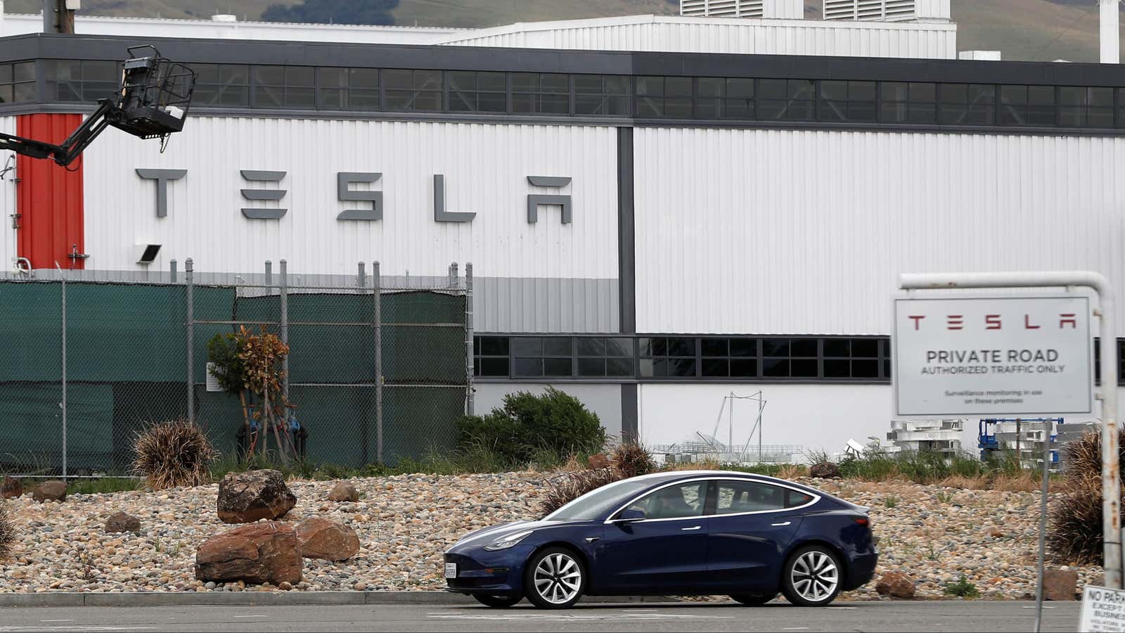 A Tesla vehicle drives past Tesla’s primary vehicle factory in Fremont, California.