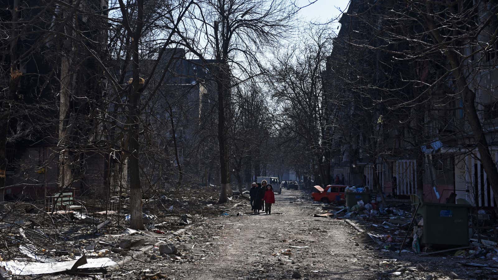 Mariupol residents walk near damaged residential buildings.