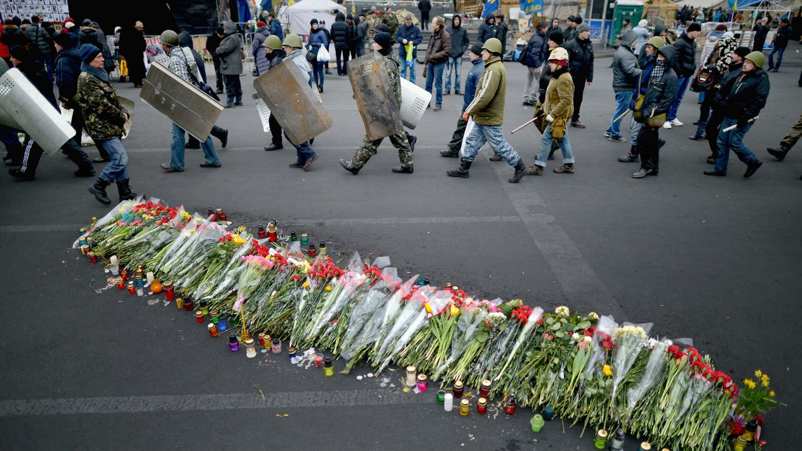 Protestors in Kiev walk past flowers for demonstrators that were killed in clashes with police.