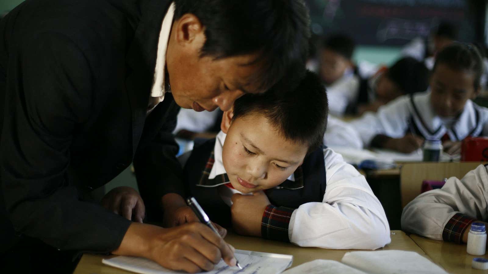 A teacher helps a boy as he writes Tibetan characters during a Tibetan language class at the Lhasa Experimental Primary School in Lhasa, China, Friday,…