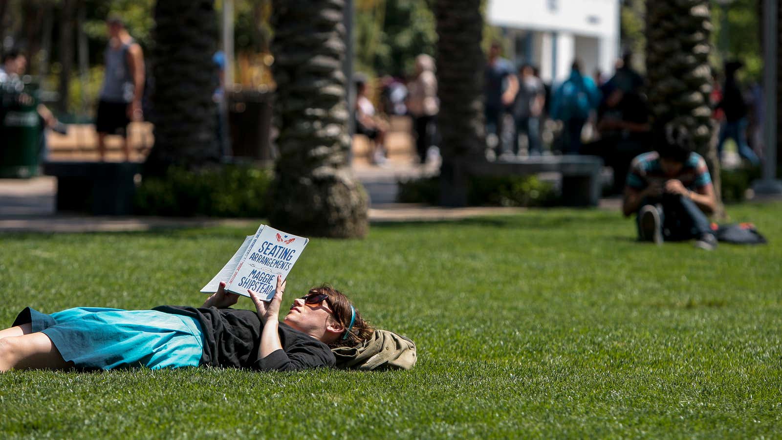 Santa Monica College English Department Assistant Ginger Pennington reads a book while lying on the lawn at Santa Monica College in Santa Monica, California April…