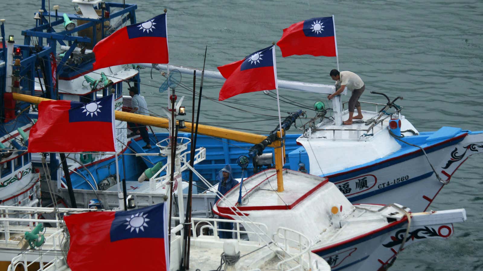 A fisherman raises a Taiwanese national flag as several dozen fishing boats set out from the Suao harbor, northeastern Taiwan, to the disputed islands in the East China Sea.