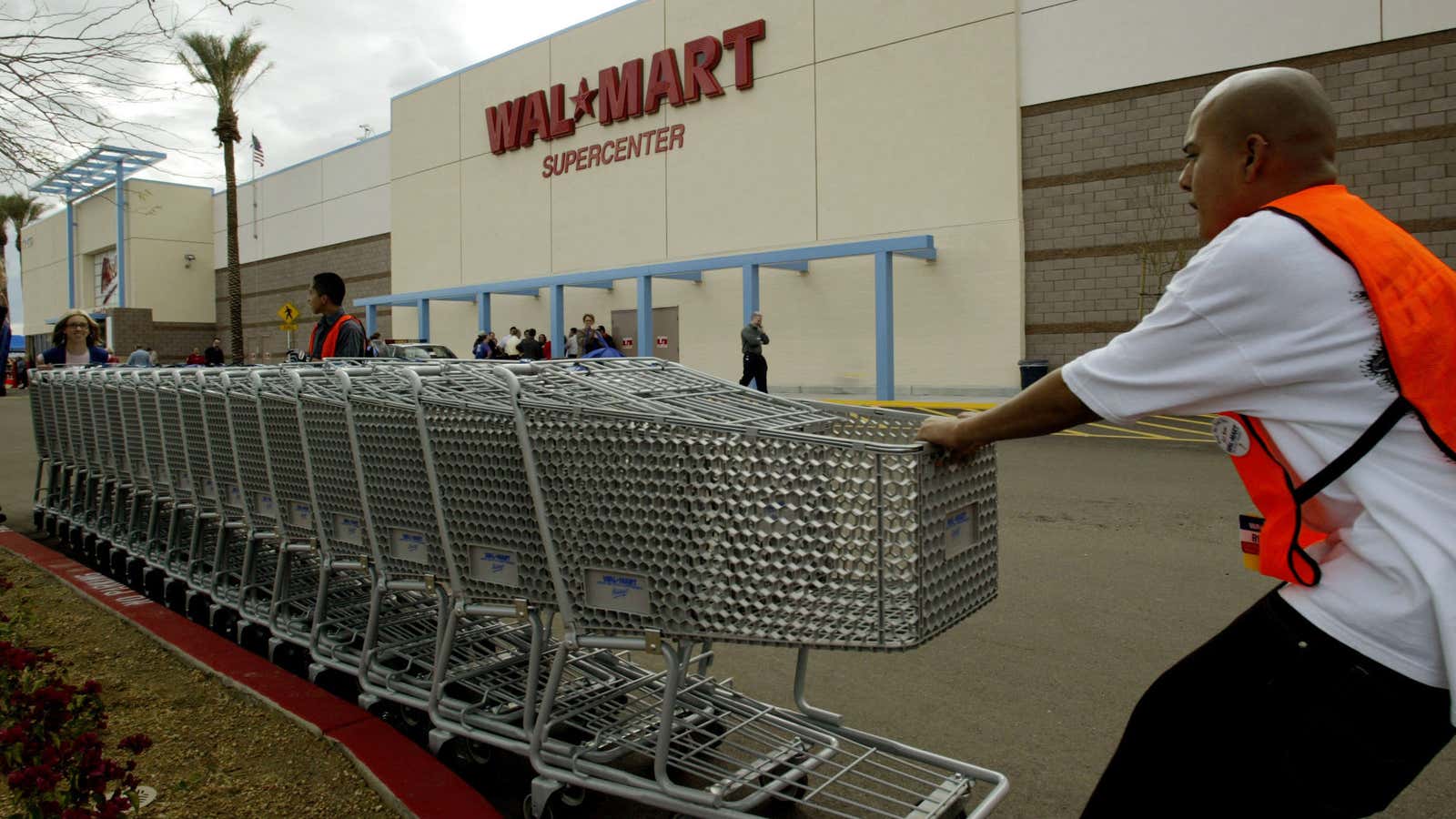 Employees move shopping carts as the first Wal Mart Supercenter to operate in the State of California, opened in La Quinta, California, March 3, 2004.…