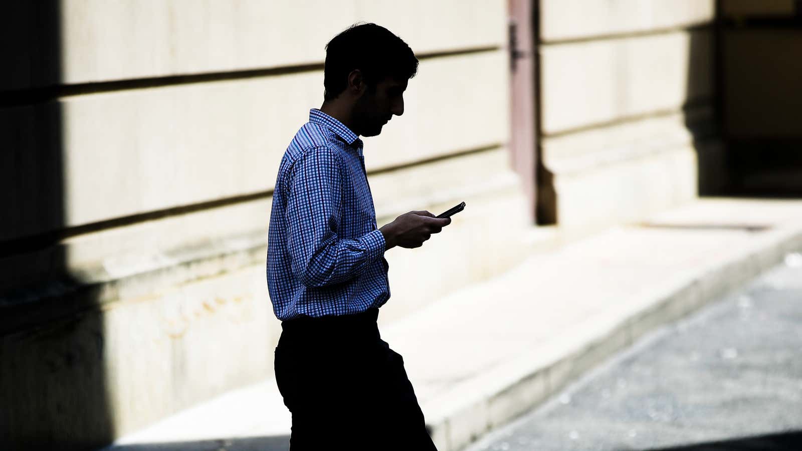 A man browses his smartphone as he walks in Philadelphia, Monday, April 8, 2019. (AP Photo/Matt Rourke)