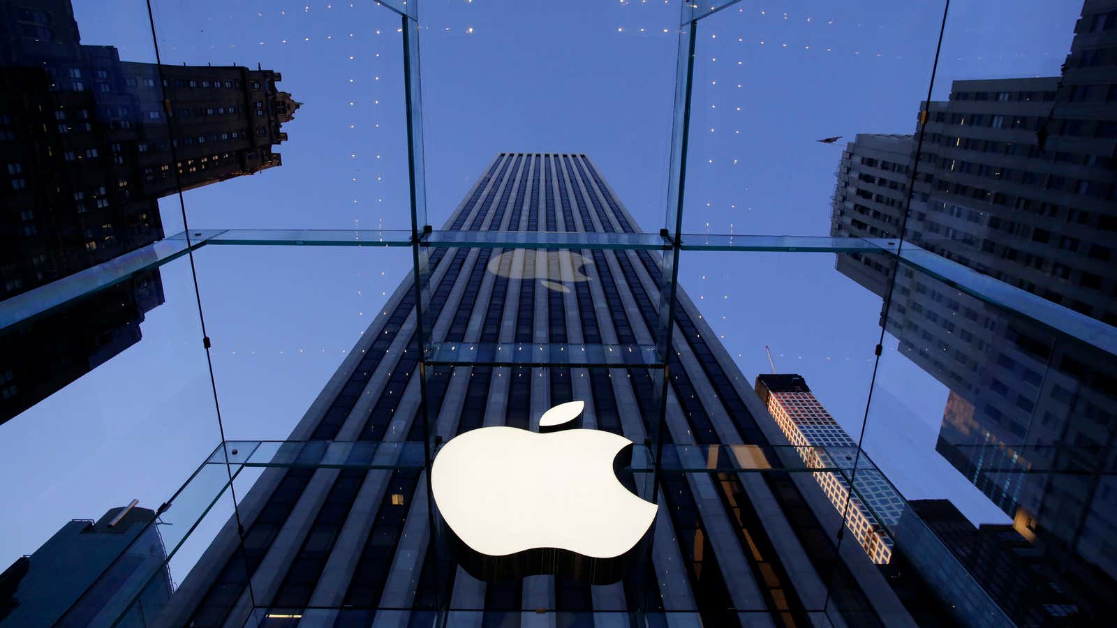 In this Sept. 5, 2014 photo, the Apple logo hangs in the glass box entrance to the company’s Fifth Avenue store, in New York. Apple…