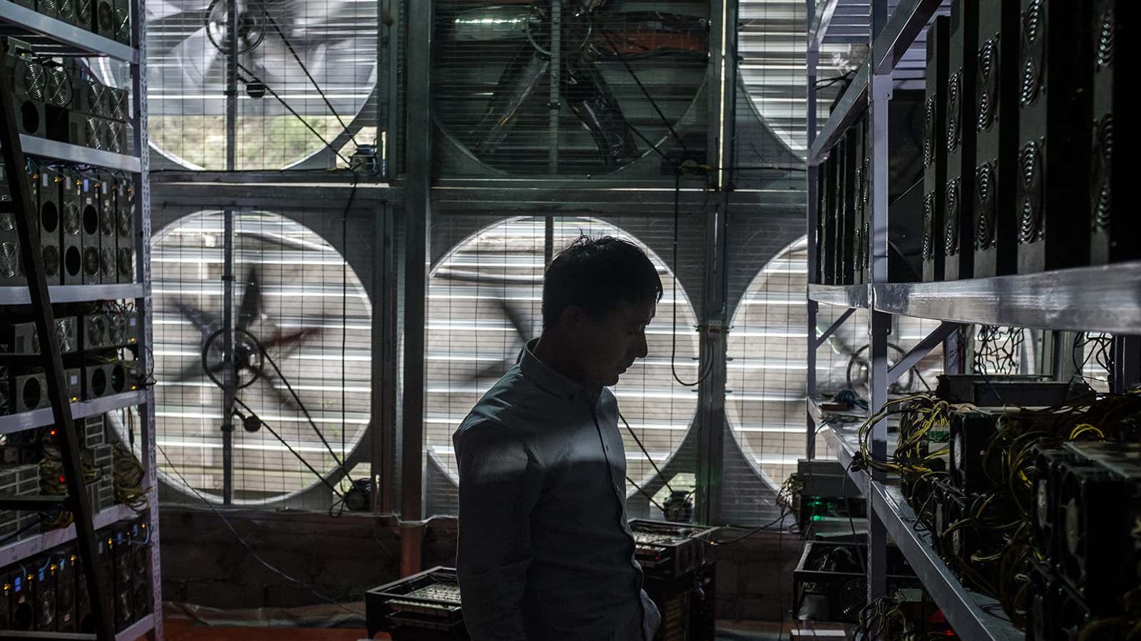 Bitcoin mine owner Liu, 29, stands in front of a wall of cooling fans at his mine where he houses and operates mining machines for miners who do not want to move to rural Sichuan.