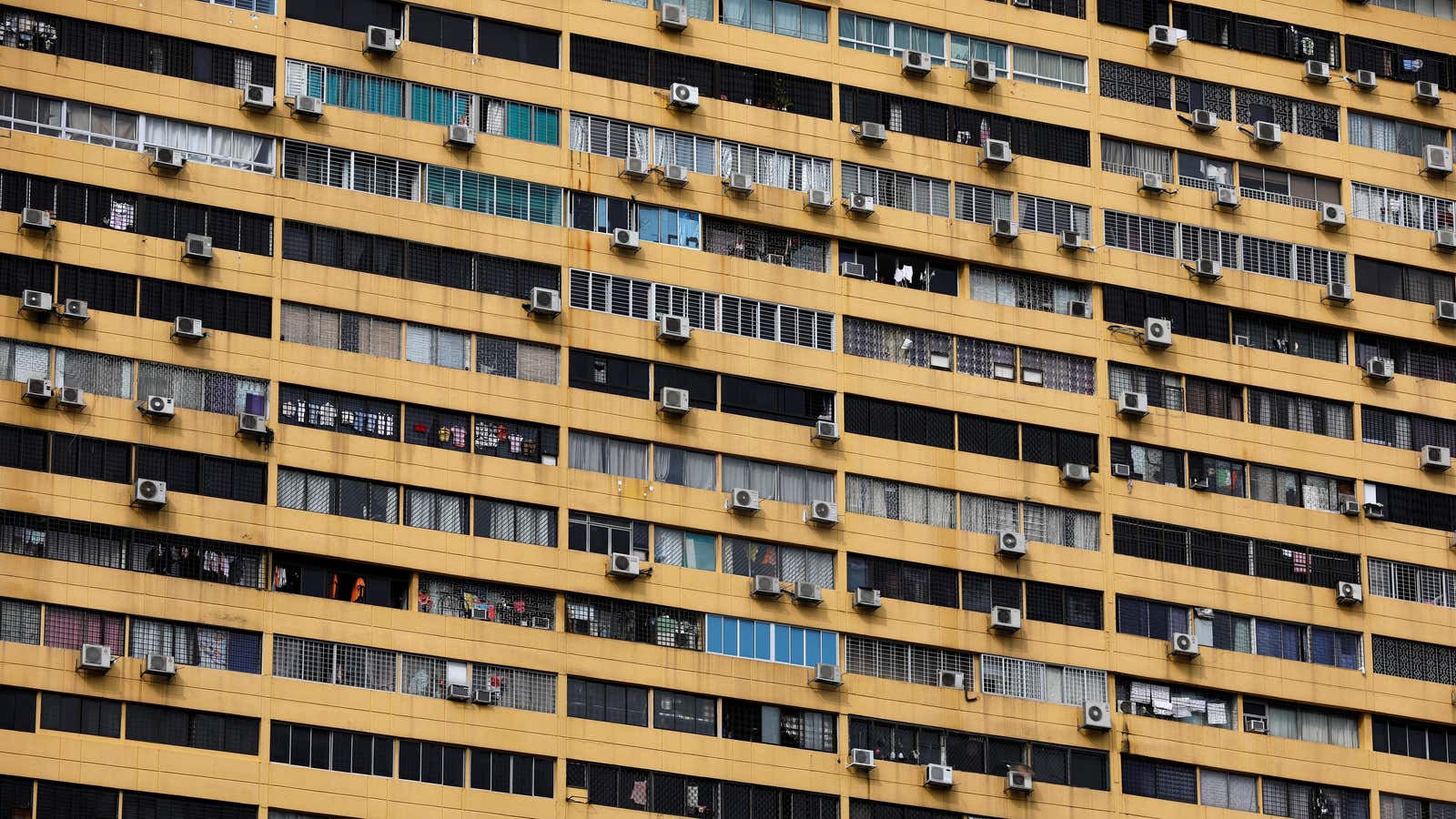 Air conditioning units dot the facade of a residential apartment block.