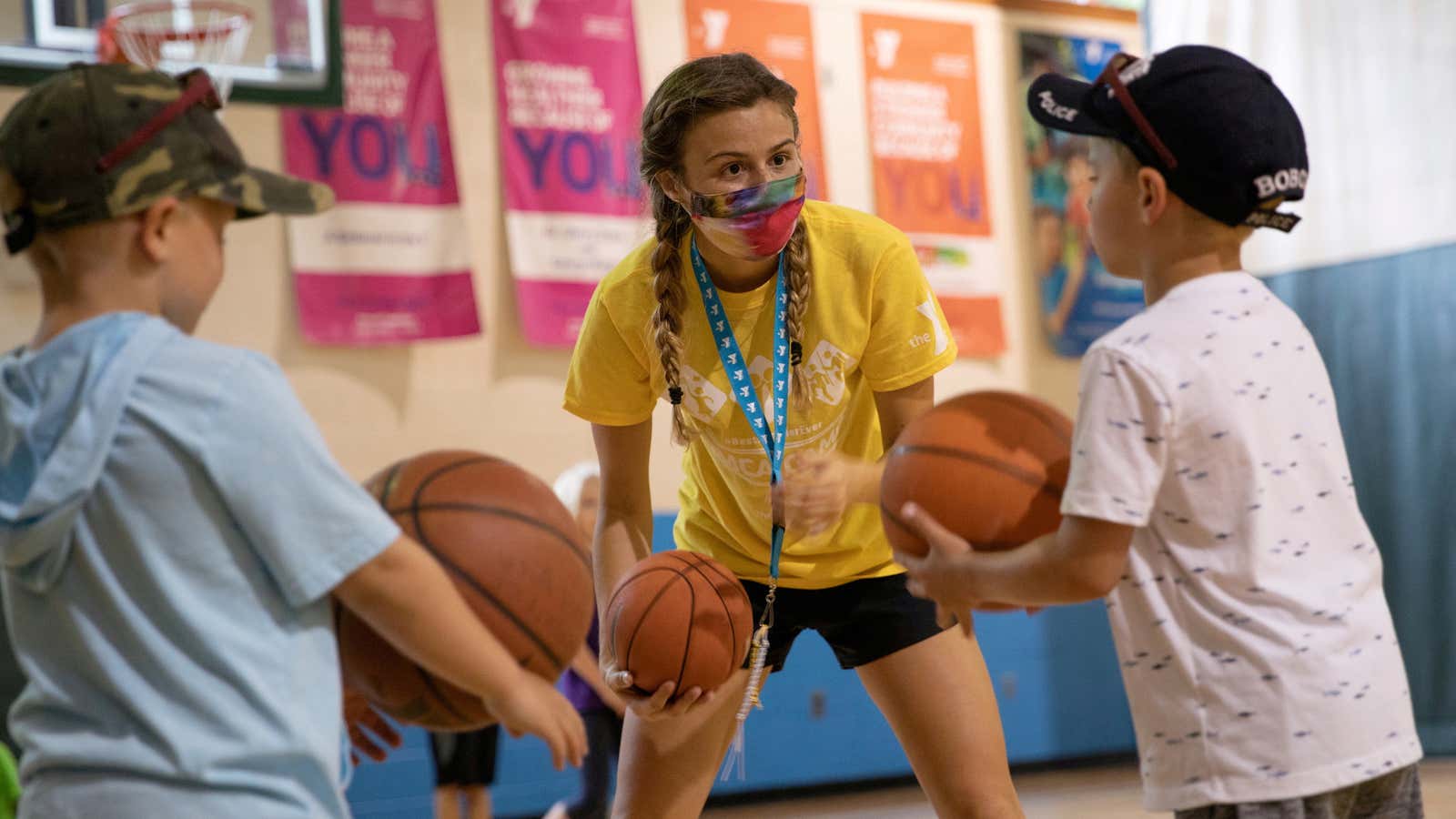 A counselor wearing a protective face mask plays with children as summer camps reopen amid the spread of coronavirus disease (COVID-19) at Carls Family YMCA…