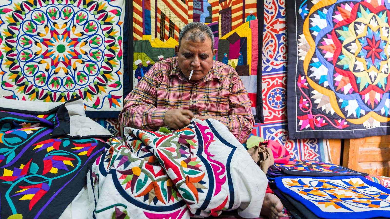 An artisan stitching a new design for a tent.