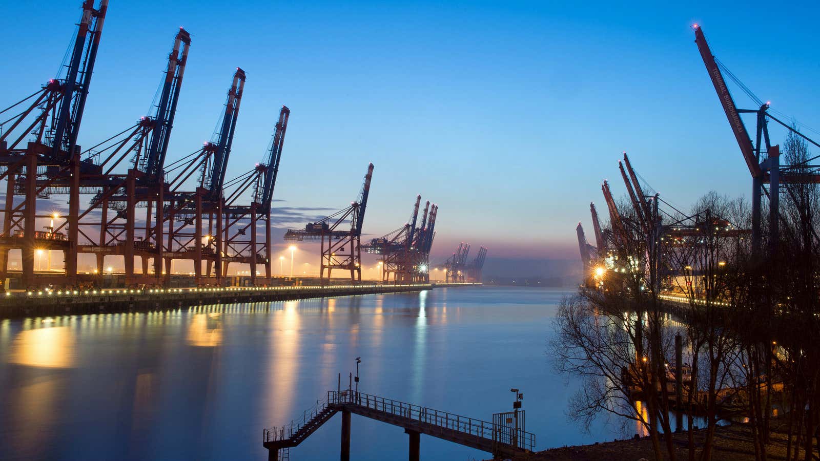 An uncharacteristically calm photo of loading cranes at a shipping terminal at the harbor in Hamburg, Germany.