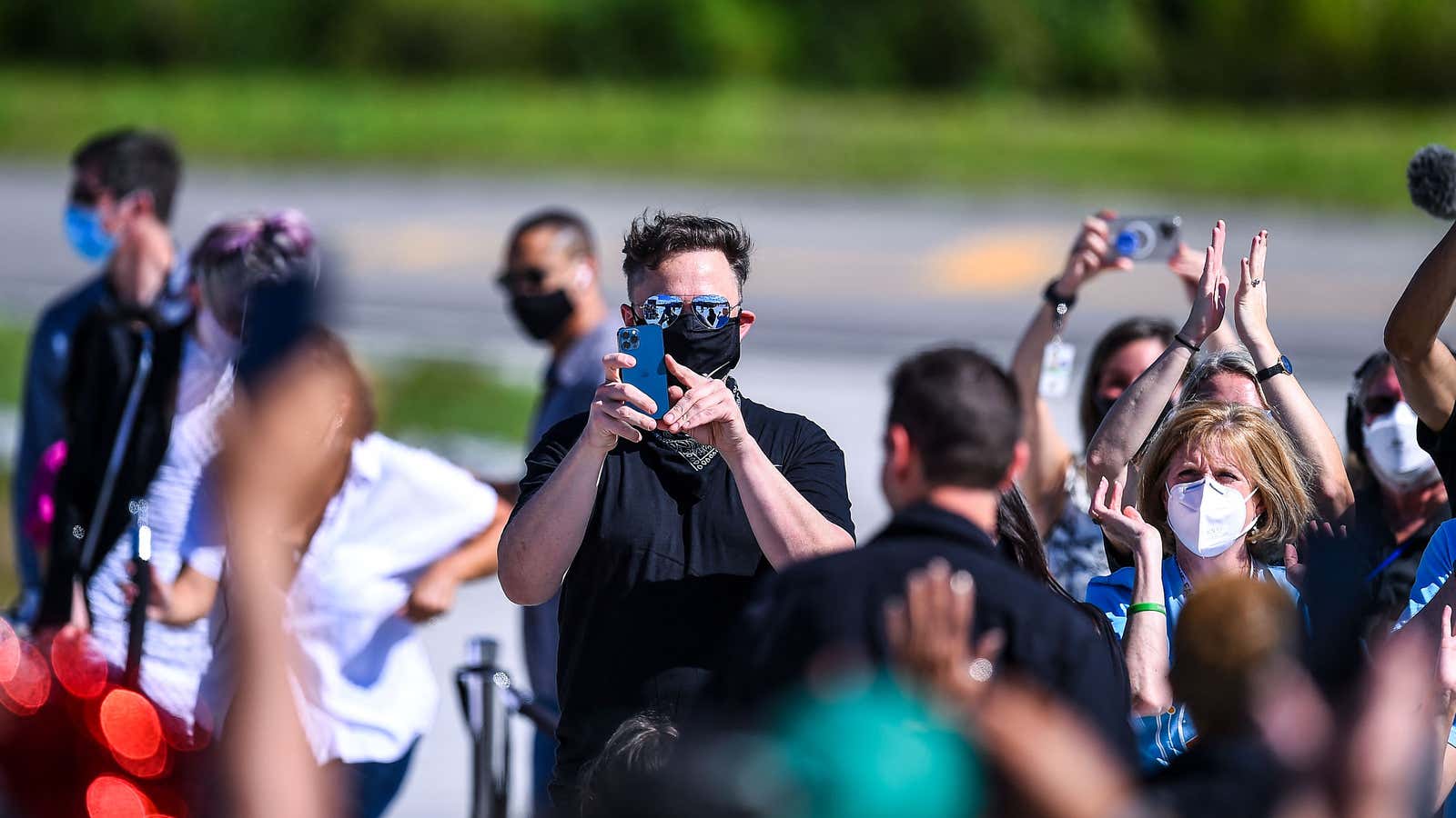 Elon Musk takes a picture on his phone during a SpaceX launch