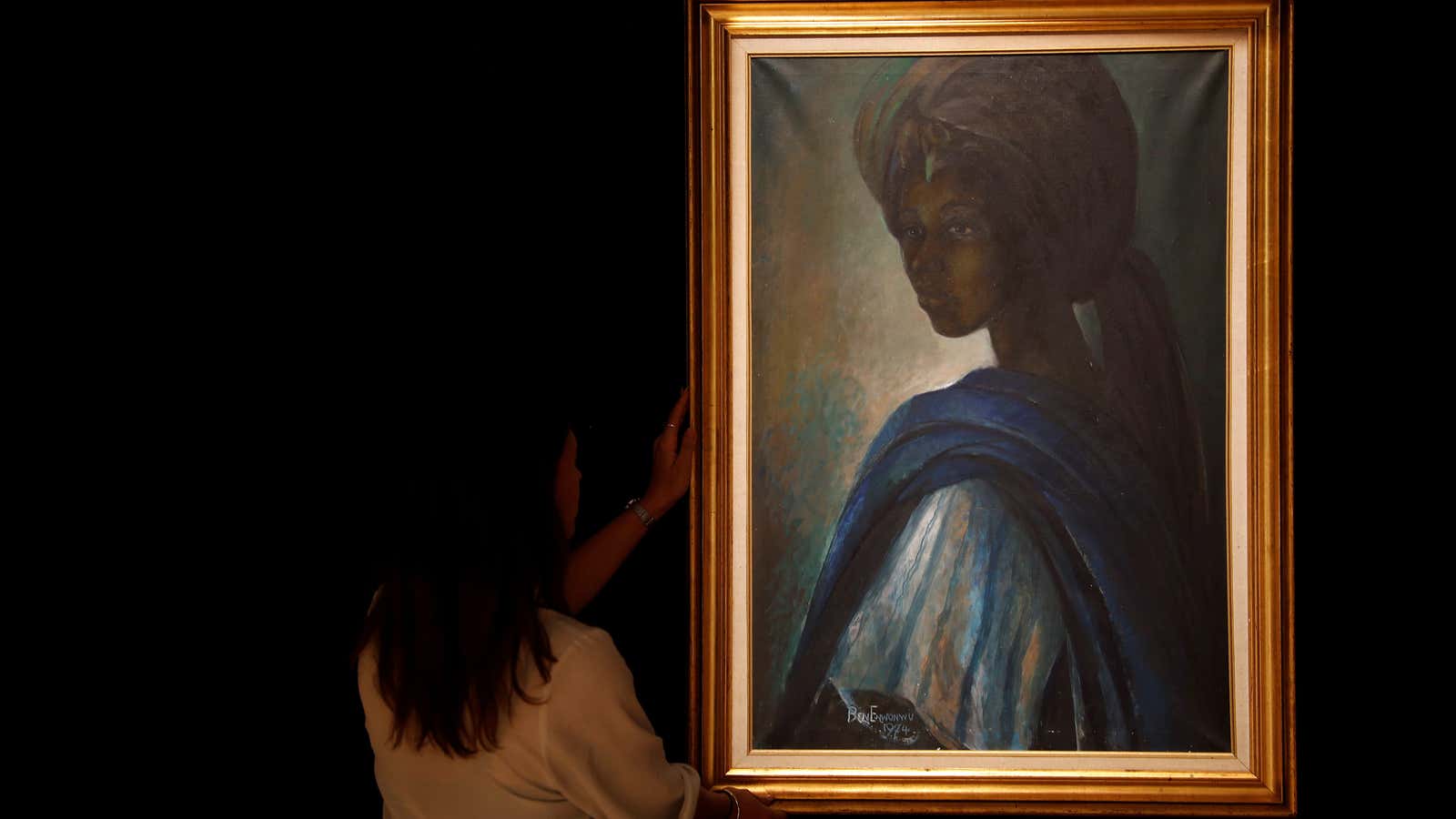 A worker at Bonhams auctioneers poses next to Tutu,” by Nigerian artist Ben Enwonwu, ahead of its sale