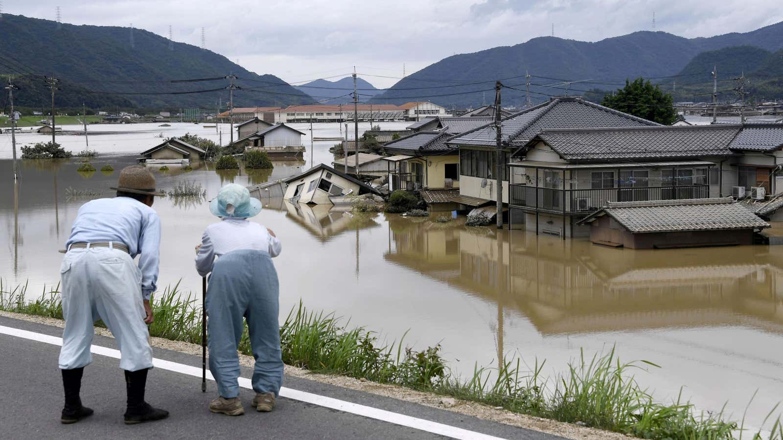 An elderly couple looks at a flooded area in Kurashiki, Okayama prefecture.