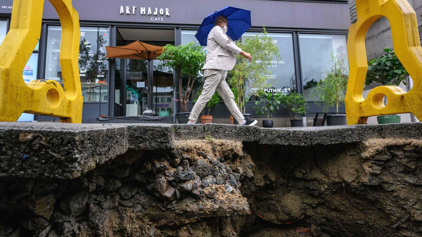 A man walks past a damaged pavement in Seoul on August 9, 2022, after record-breaking rains caused severe flooding. 