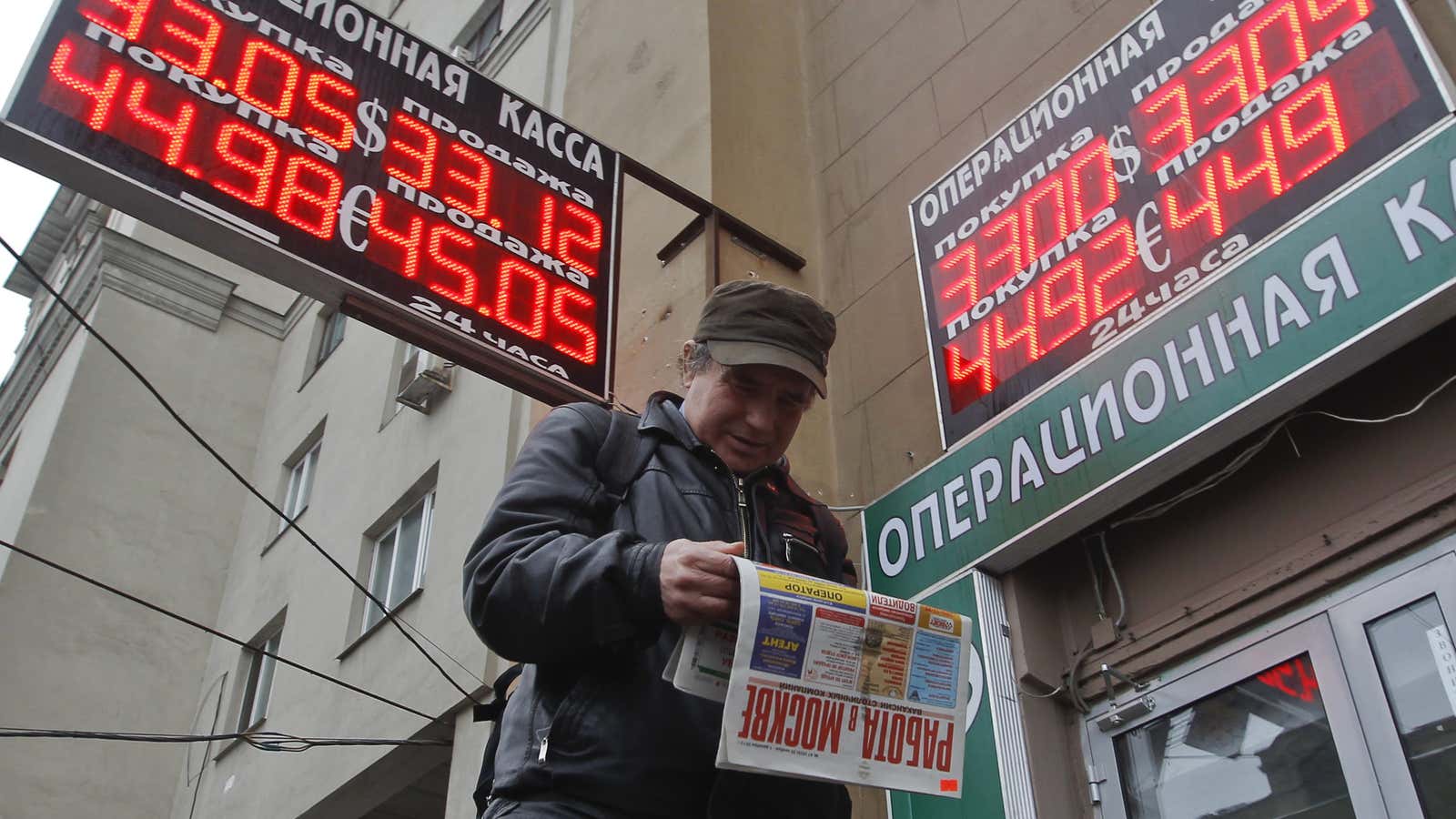 A man reads a newspaper under signs with currency exchange rates in Moscow, November 28, 2013. Senior Russian policy makers played down the weakness of…