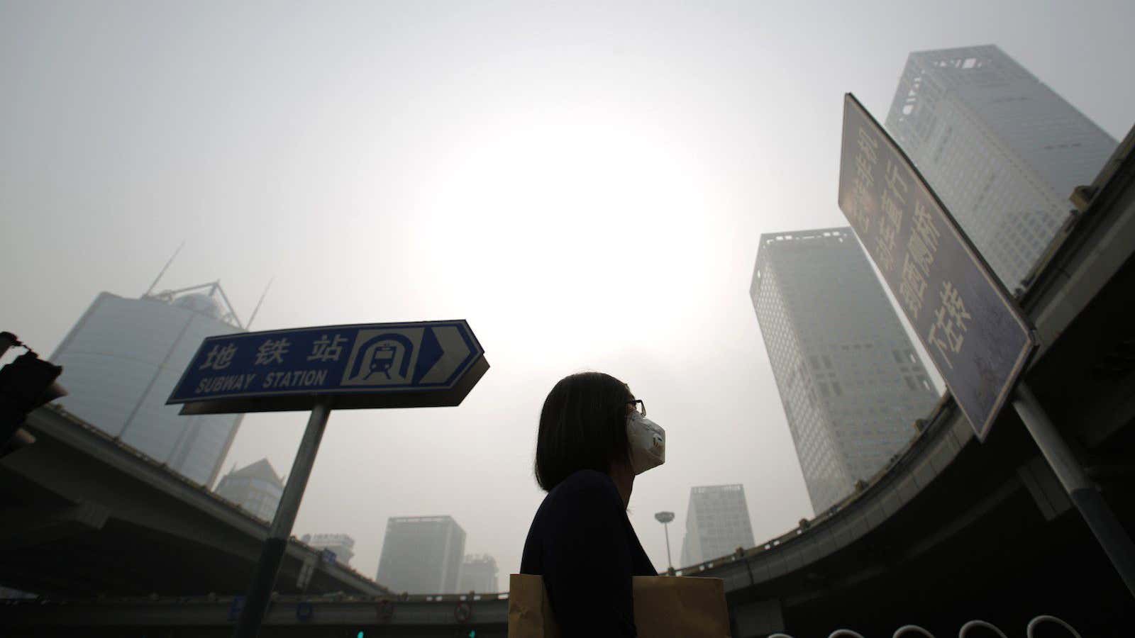 A woman wearing a mask makes her way on a street amid heavy haze and smog in Beijing.