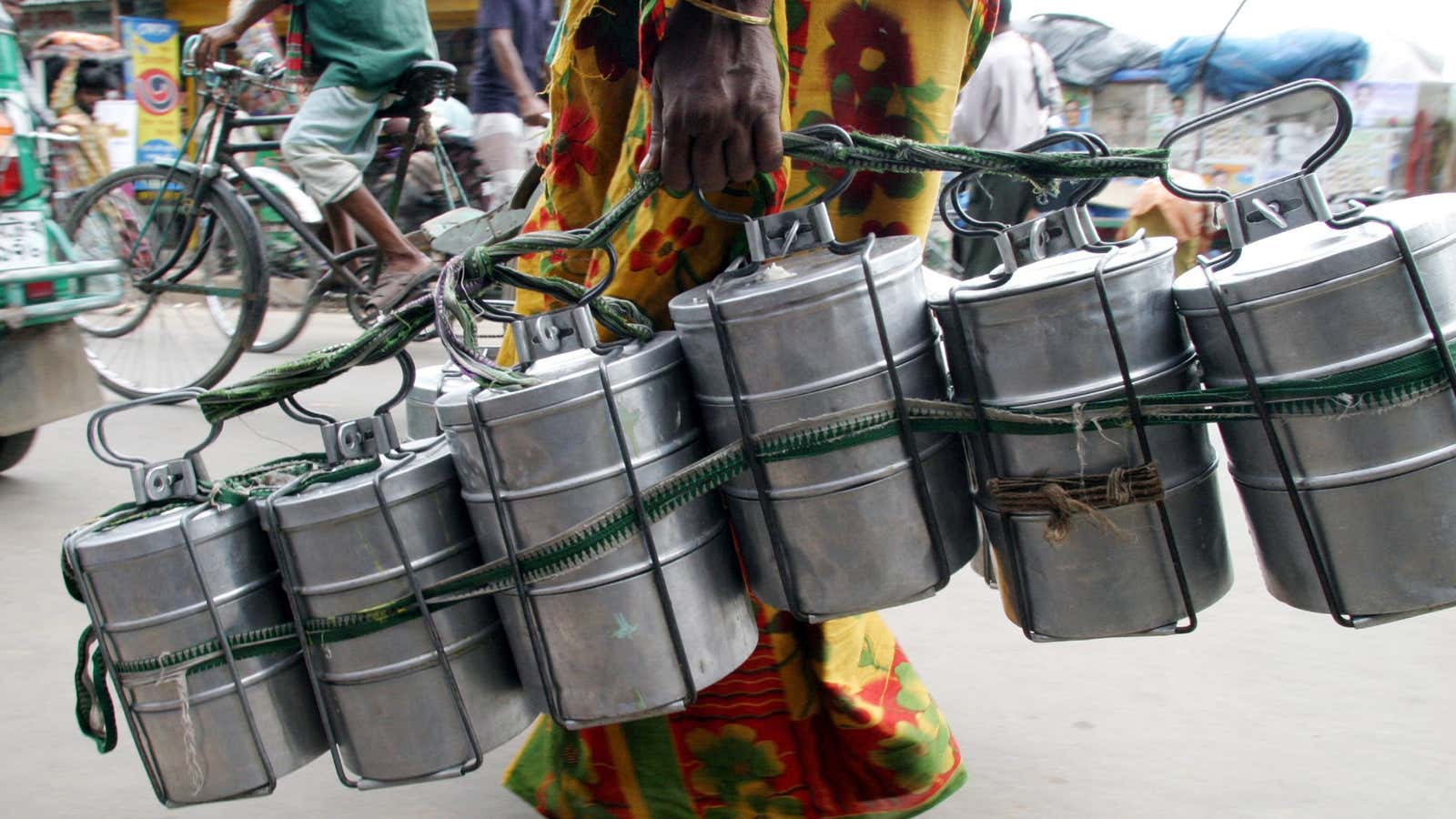 A Bangladeshi woman carries food in tiffin carriers to supply to different shops and offices in Dhaka July 19,2005. Many poor people in Dhaka city earn their living by collecting food from different homes and delivering it to workers. A tiffin carrier earns 100 taka ($1.56) a month. REUTERS/Rafiqur Rahman  RR/YH – RP6DRMRTGPAC