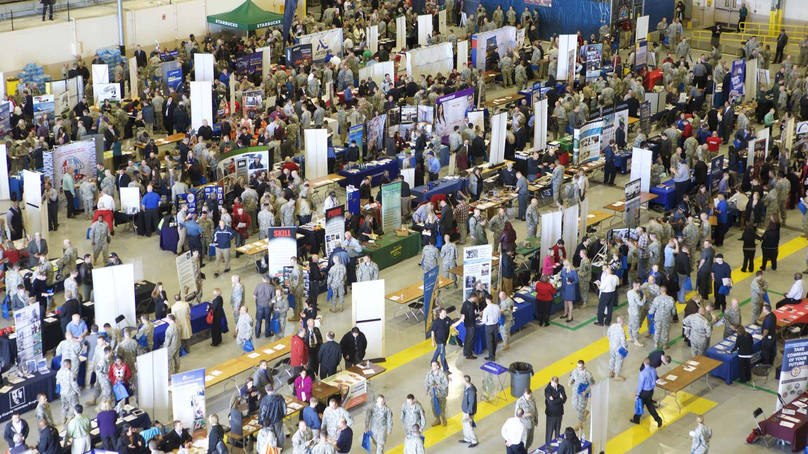 A crowd of service members, veterans and military spouses speak with employers during the Washington State Service Member for Life Transition Summit job fair on…