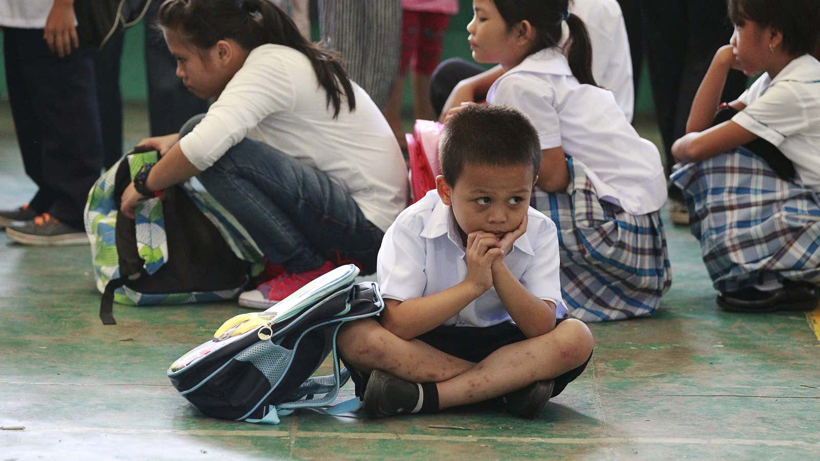 A boy sits on the floor as he waits with other students at Baclaran Elementary School in Paranaque City, metro Manila.
