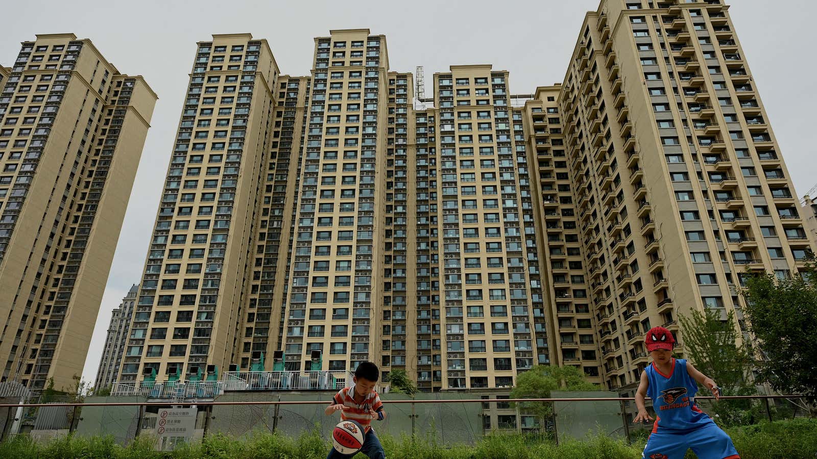 Children play basketball in front of a housing complex by Chinese property developer Evergrande in Beijing on July 28, 2022.