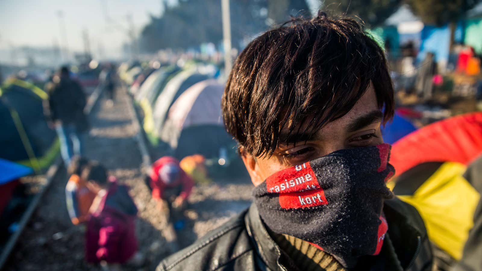 A man with a scarf covering his face stands in a transit camp for migrants and refugees on the Greek side of the Greek-Macedonian border near Idomeni, Greece, Mar. 11 2016.