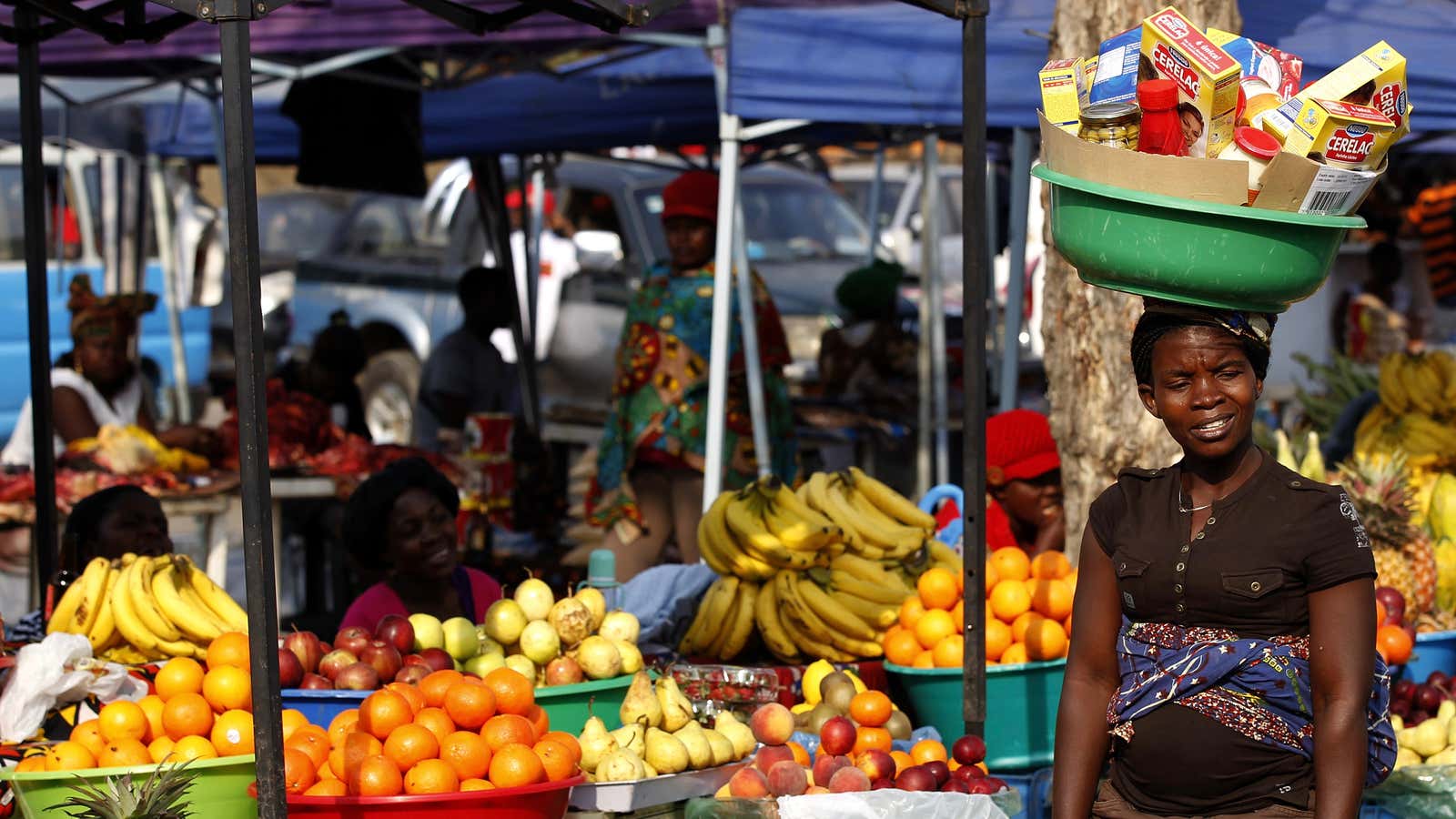 A zangueira vendor with her baby and her wares in Luanda, Angola.