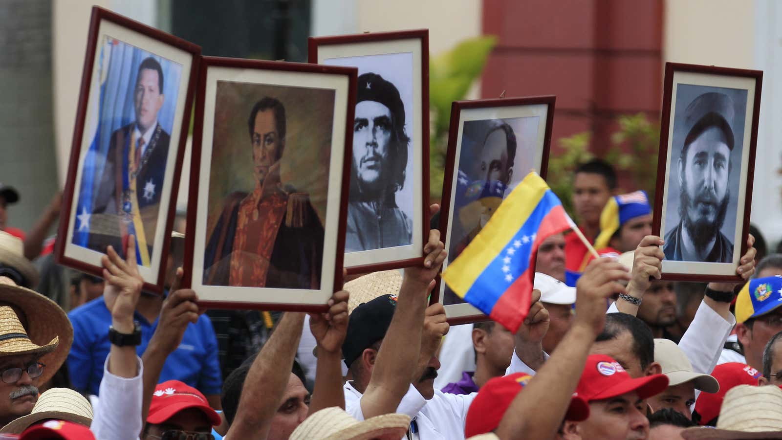 Cuban doctors hold up framed pictures (L-R) of late President Hugo Chavez, Venezuela’s National hero Simon Bolivar, Ernesto ‘Che’ Guevara, Cuban national hero Jose Marti…