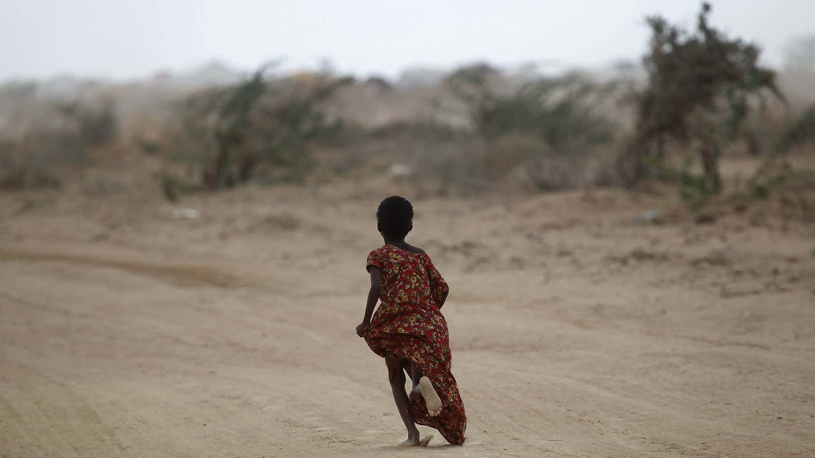 A young girl fleeing the Somali famine in 2011 runs in search of her parents.